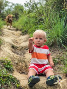 Man Cheung Po-babys first hike 2018- baby sitting on dirt with dog behind him