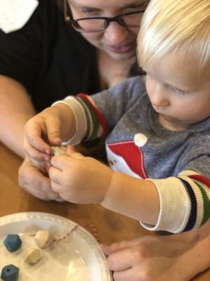 toddler using fine motor skills to thread a bead on a wire